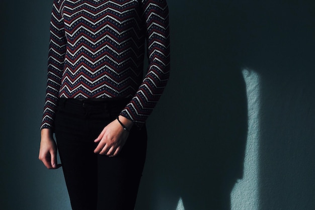 Midsection of woman standing against wall