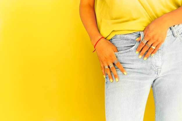 Midsection of woman standing against yellow background