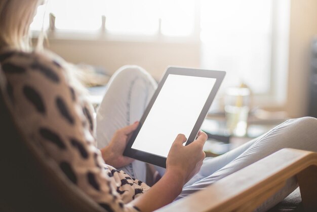 Midsection of woman using digital table while sitting on chair at home