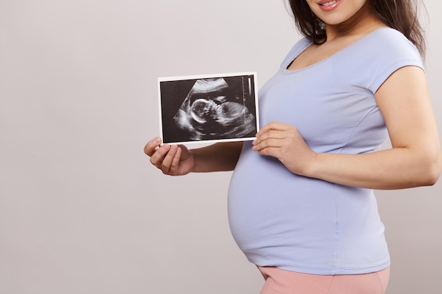 Midsection of woman using digital tablet while standing against wall