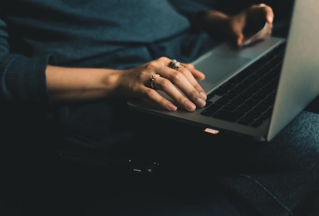 Midsection of woman using laptop on sofa