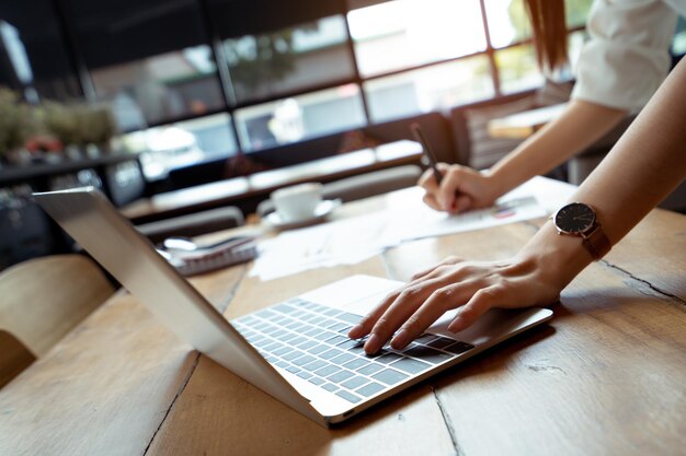 Midsection of woman using laptop on table in cafe