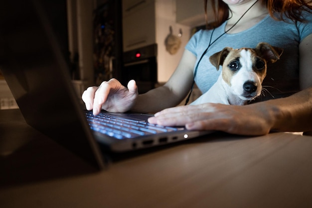 Foto sezione centrale di una donna che usa un portatile con un cane