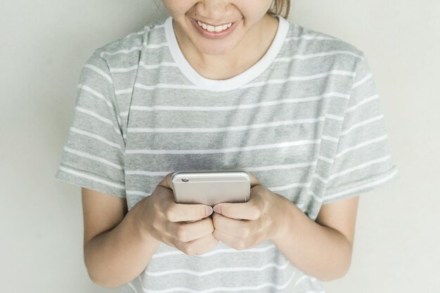 Midsection of woman using mobile phone against gray background