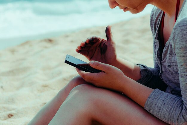 Photo midsection of woman using mobile phone at beach