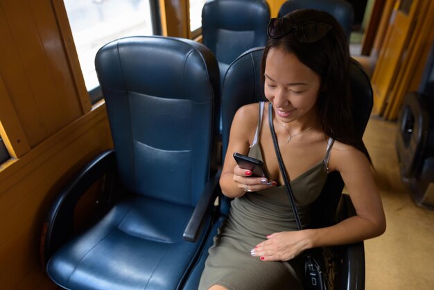 Foto sezione centrale di una donna che usa il telefono cellulare in autobus