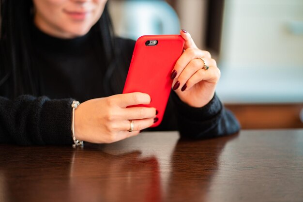 テーブルで携帯電話を使っている女性のミッドセクション