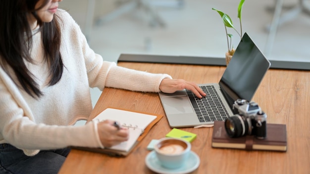 Midsection of woman using mobile phone while sitting on table