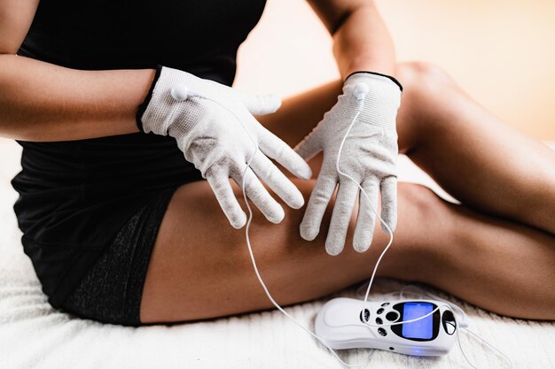 Midsection of woman wearing gloves while sitting on bed