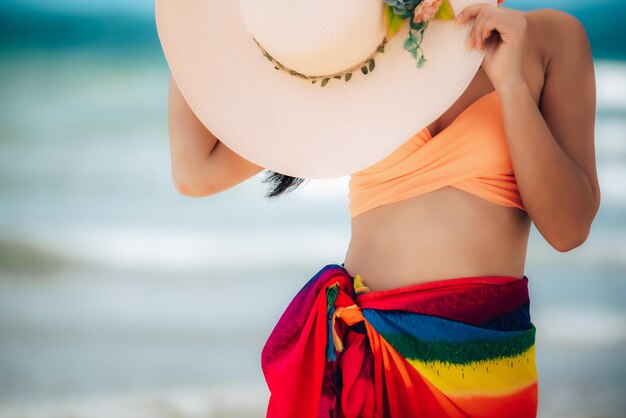 Midsection of woman wearing hat while standing on beach