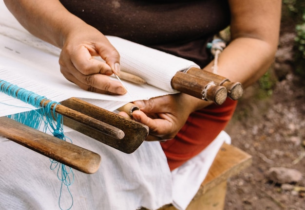 midsection of woman weaving on loom