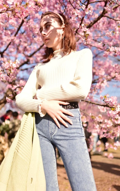 Midsection of woman with arms raised standing against tree