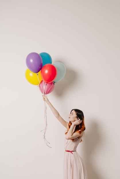 Midsection of woman with balloons against white background