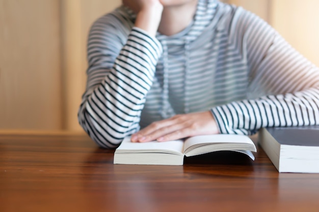 Midsection of woman with book sitting on table at home