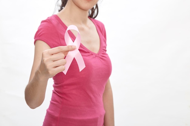 Midsection of woman with breast cancer awareness ribbon standing against white background