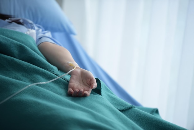 Foto sezione centrale di una donna con una flebo sul letto dell'ospedale