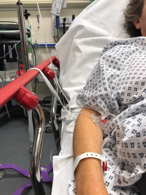 Photo midsection of woman with iv drip lying on bed in hospital