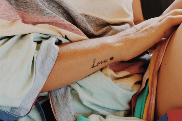 midsection of woman with love tattoo on hand