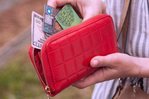 Foto sezione centrale di una donna con banconote e carte di credito in borsa rossa