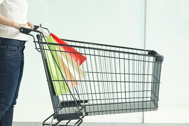 Photo midsection of woman with shopping bags in cart against wall