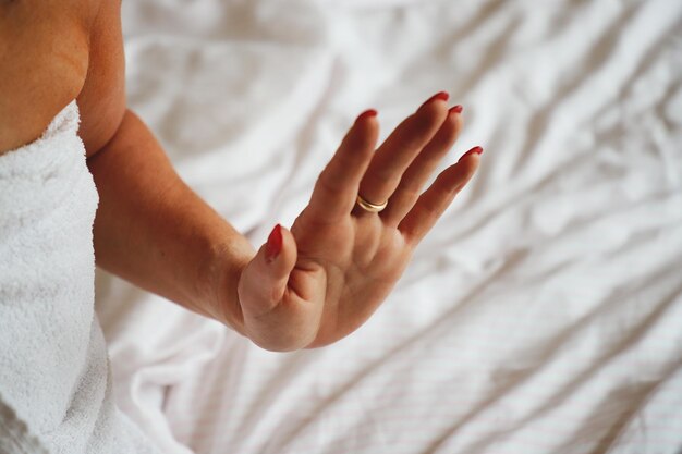 Photo midsection of woman wrapped in towel sitting on bed at home