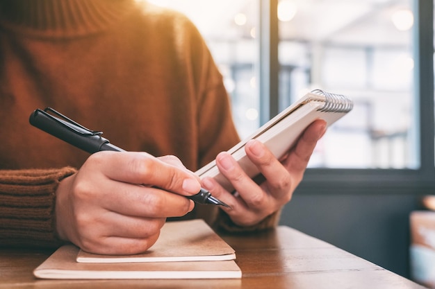 Foto sezione centrale di una donna che scrive in un libro sul tavolo