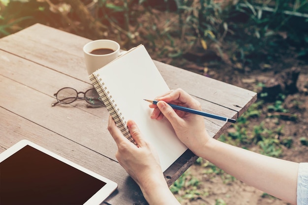 Midsection of woman writing in book on table