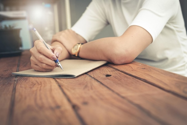 Foto sezione centrale di una donna che scrive in un libro sul tavolo