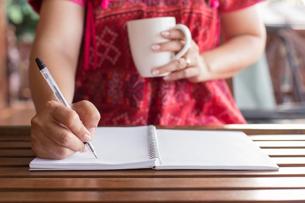 Photo midsection of woman writing in book on table