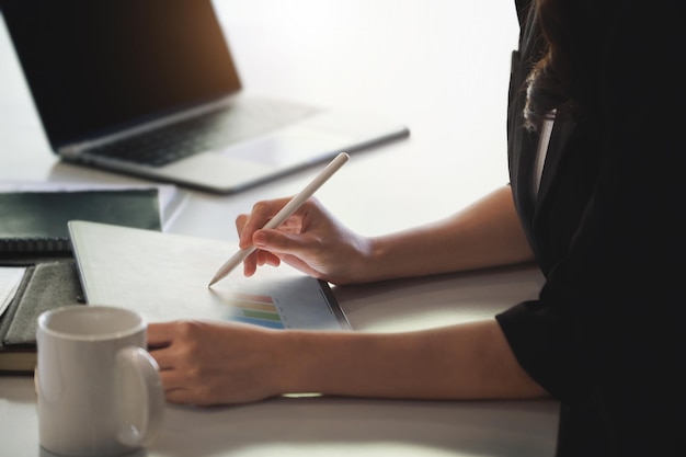 Foto sezione centrale di una donna che scrive in un libro al tavolo