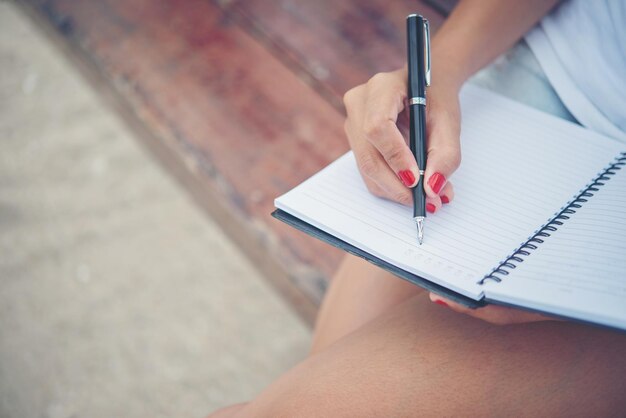 Foto sezione centrale di una donna che scrive in un libro