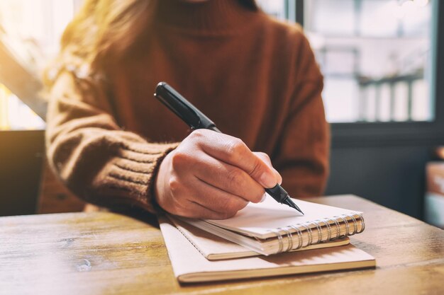 Foto sezione centrale di una donna che scrive su un taccuino al tavolo