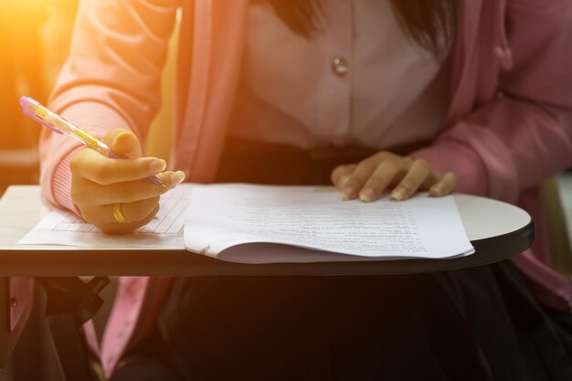 Midsection of woman writing on paper while sitting on table