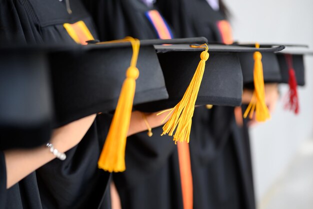 Foto sezione centrale di donne che indossano abiti da laurea che tengono cartoni di malta