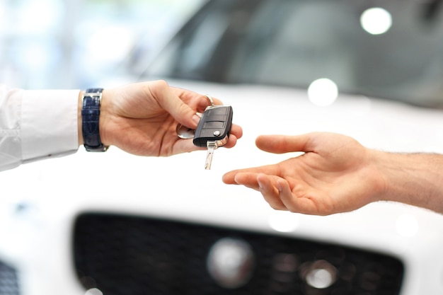 midsection of young couple buying new car in showroom