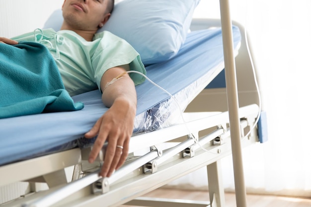 Midsection of young man lying on bed at hospital