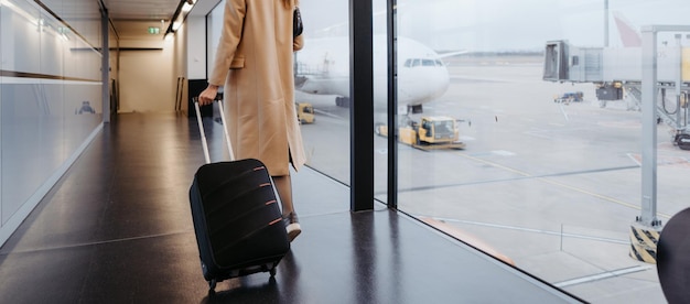 Foto midsectiontraveler gaat op zakenreis wandelen met koffer op de luchthaven