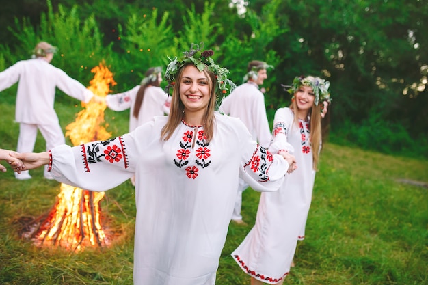 В середине лета. Молодые люди в славянской одежде вращаются вокруг пожара в середине лета. ,