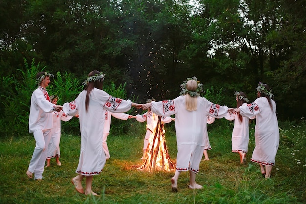 Midzomer. jongeren in slavische kleren dansen rond een kampvuur in het bos.