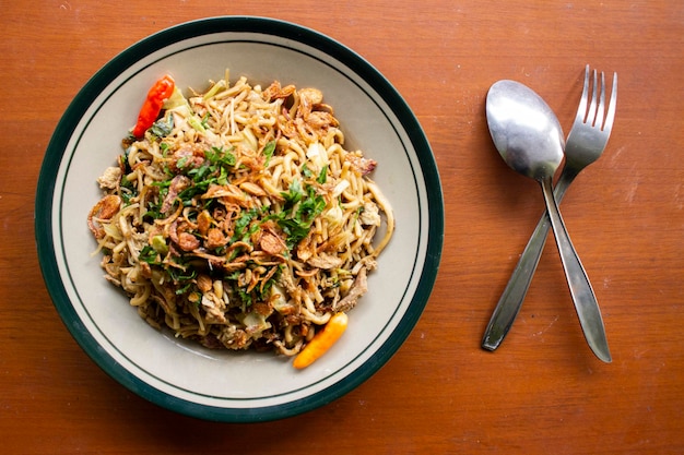 Mie Goreng Jawa or bakmi jawa or java noodle with spoon and fork Indonesian traditional street food noodles from central java or Yogyakarta indonesia on wood background