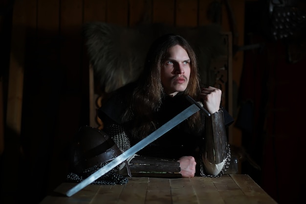 Photo a mighty hero with long hair in chain mail armor in an ancient hall. medieval warrior in the knight's chambers.