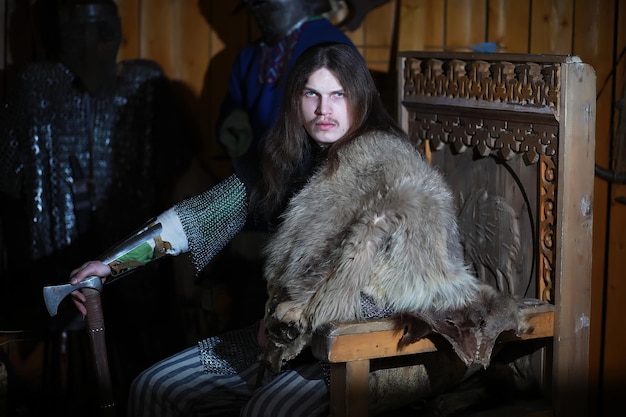 A mighty hero with long hair in chain mail armor in an ancient hall. Medieval warrior in the knight's chambers.