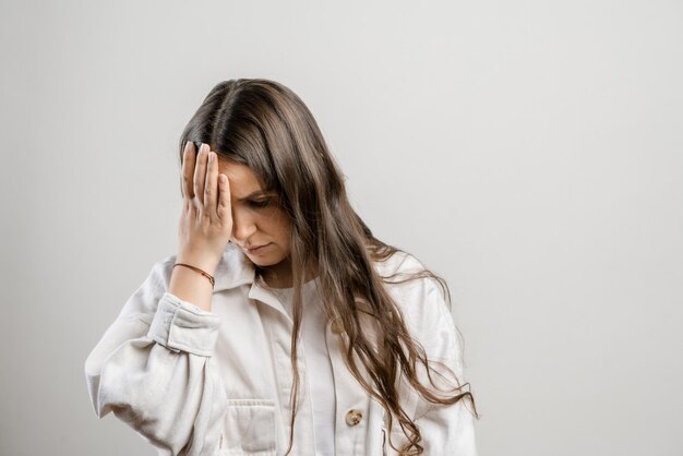 Migraine and headaches in women Brunette girl with long hair on a gray background