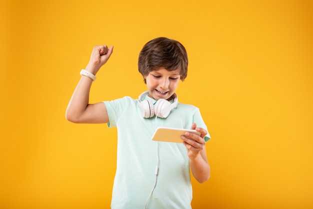 Mijn opwinding. Overweldigde donkerharige schooljongen die zijn telefoon gebruikt en zijn koptelefoon op heeft