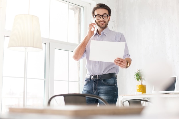 Mijn plan. professionele jonge man praten aan de telefoon en met een vel papier