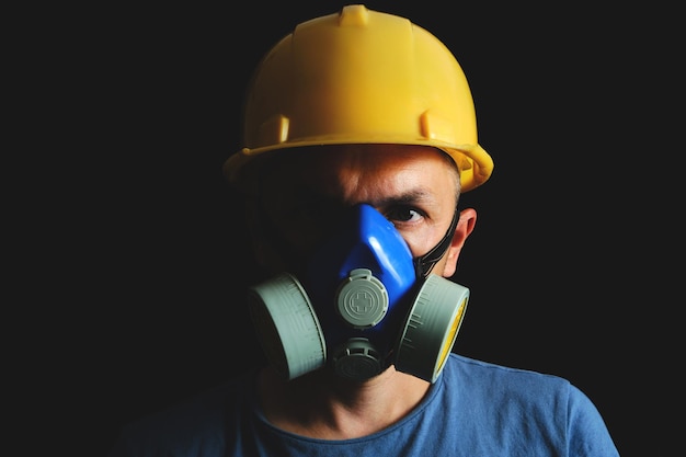 Mijnwerker in gele helm en gasmasker op zwarte achtergrond. kolenindustrie, veiligheid en bescherming.