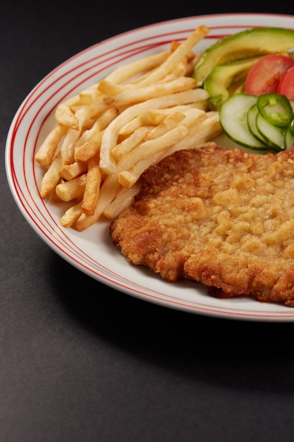 사진 milanesa de pollo con papas fritas y ensalada de pepino tomate y aguacate