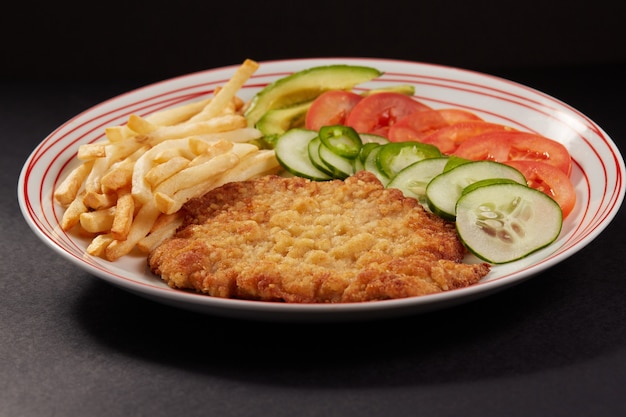 사진 milanesa de pollo con papas fritas y ensalada de pepino tomate y aguacate