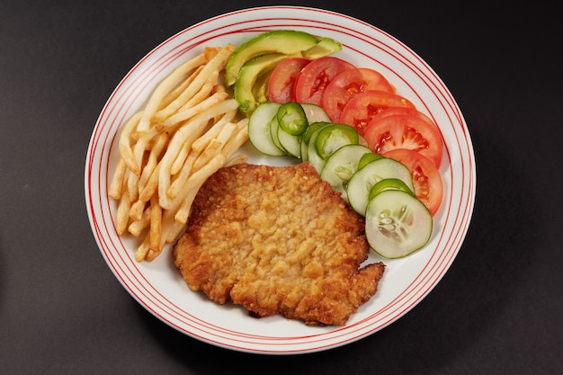 사진 milanesa de pollo con papas fritas y ensalada de pepino tomate y aguacate