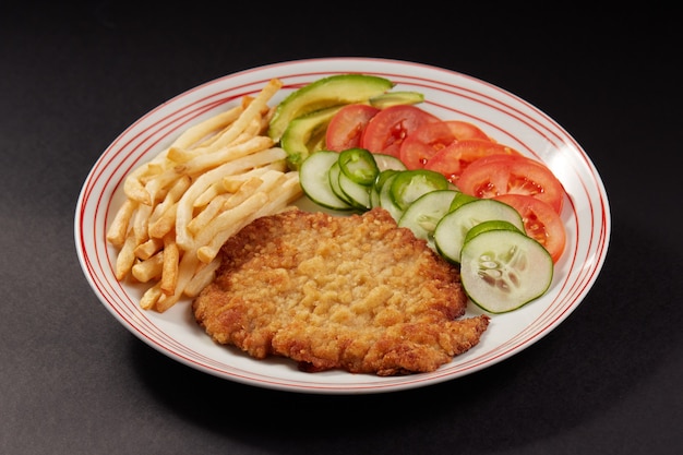 사진 milanesa de pollo con papas fritas y ensalada de pepino tomate y aguacate